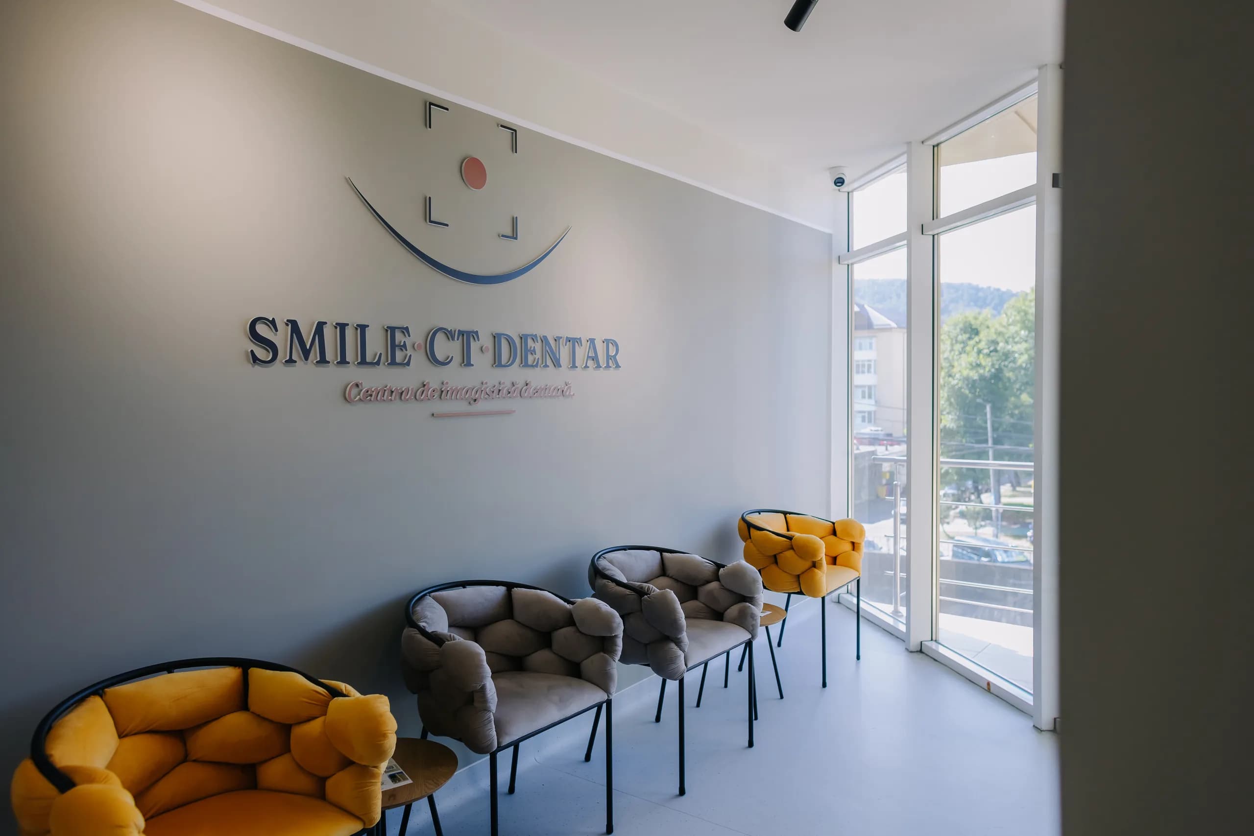 Sala de așteptare a centrului, cu sigla pe perete și fotoliile galbene